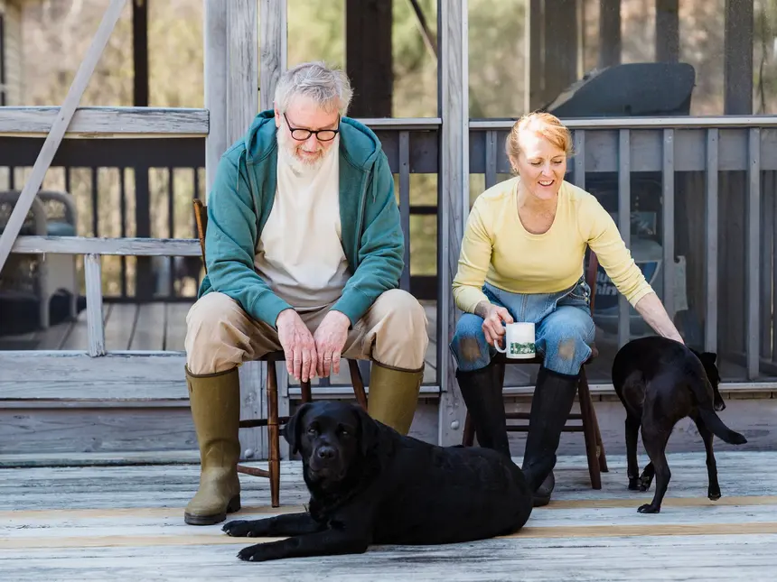 An older couple sitting together on the porch of their home